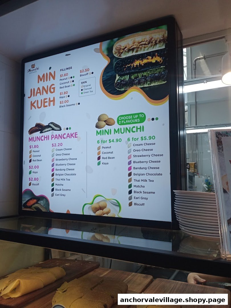 A brightly lit digital menu board for Munchi Pancakes, displaying various pancake and kueh options.