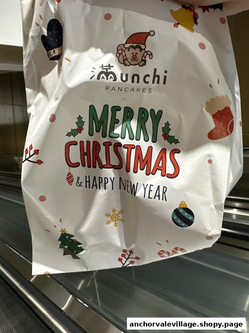 A festive white paper bag from Munchi Pancakes, featuring a 'Merry Christmas & Happy New Year' design.