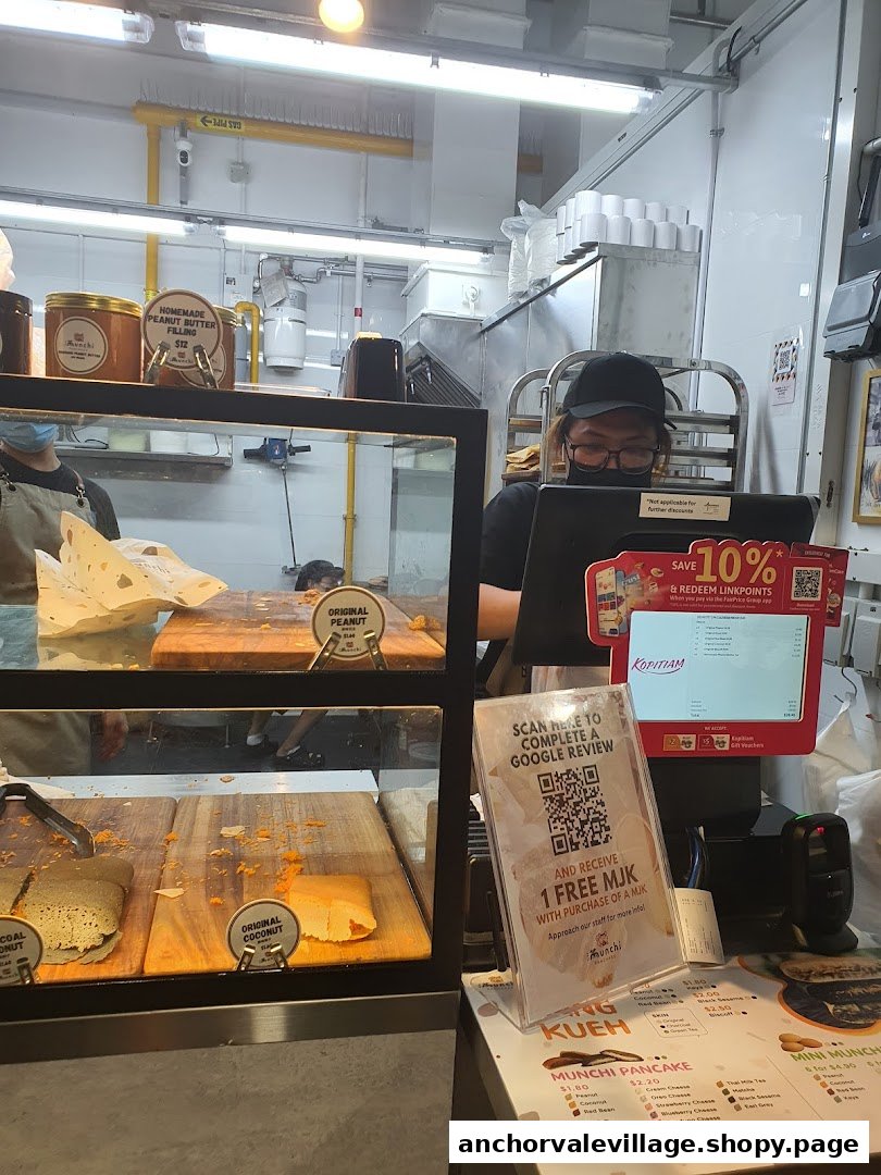 A staff member at Munchi Pancakes' counter with display cases showing various pancakes and fillings.