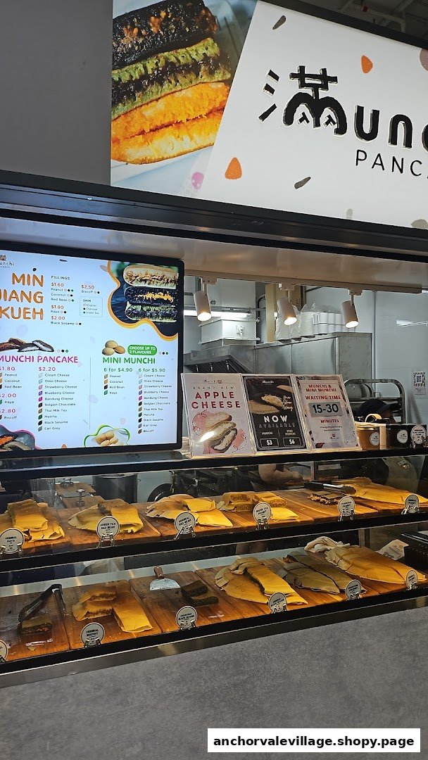 A digital menu board displaying pancake varieties and prices, alongside a display counter with products.
