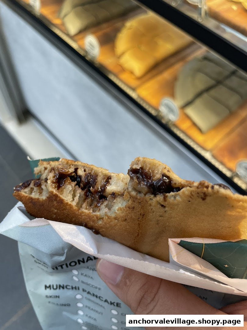 A hand holds a delicious, bitten Munchi Pancake revealing its rich chocolate filling.