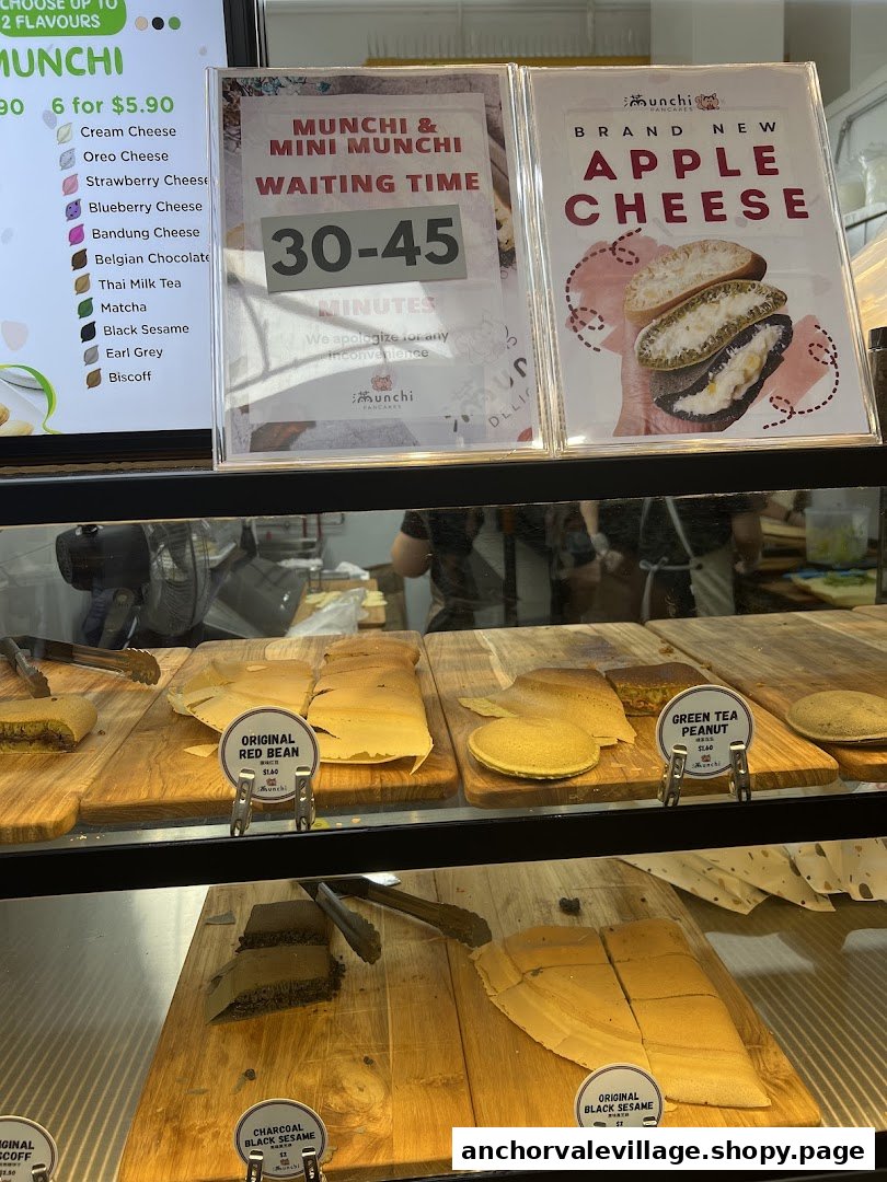 A display case at Munchi Pancakes showcasing various pancake flavors, a menu board, and promotional signs.