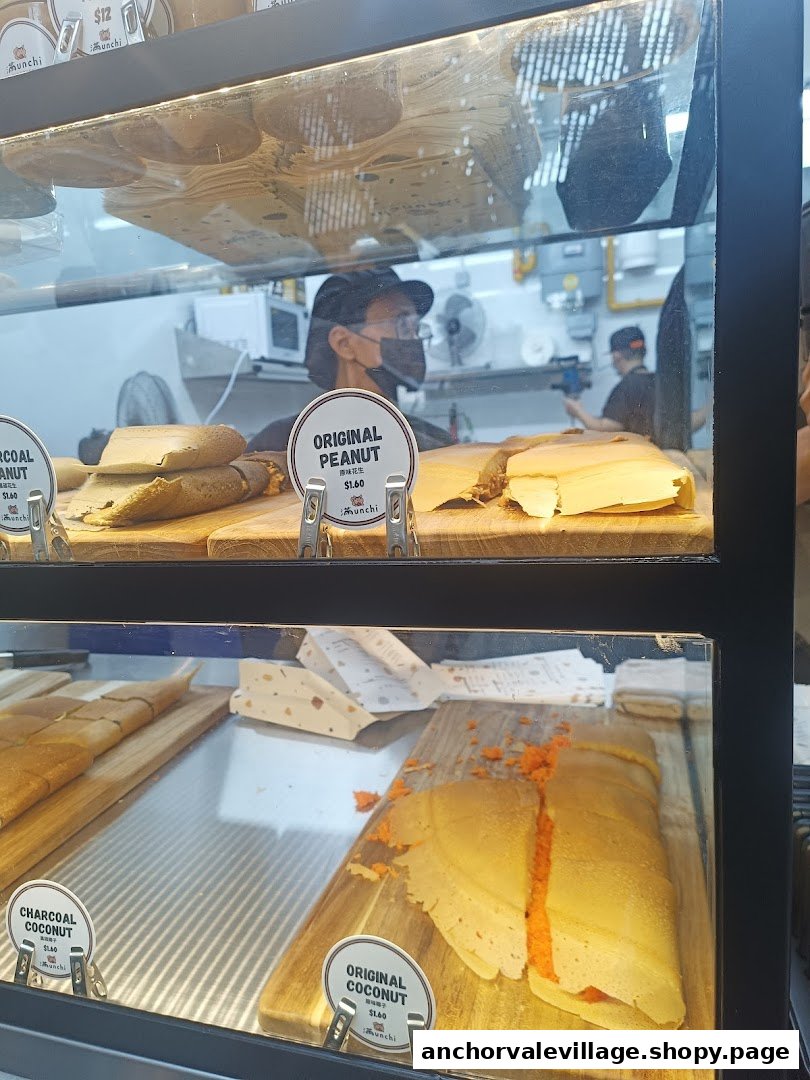 A display case showcases various Munchi pancakes, including Original Peanut and Charcoal Coconut, with staff visible in the background.