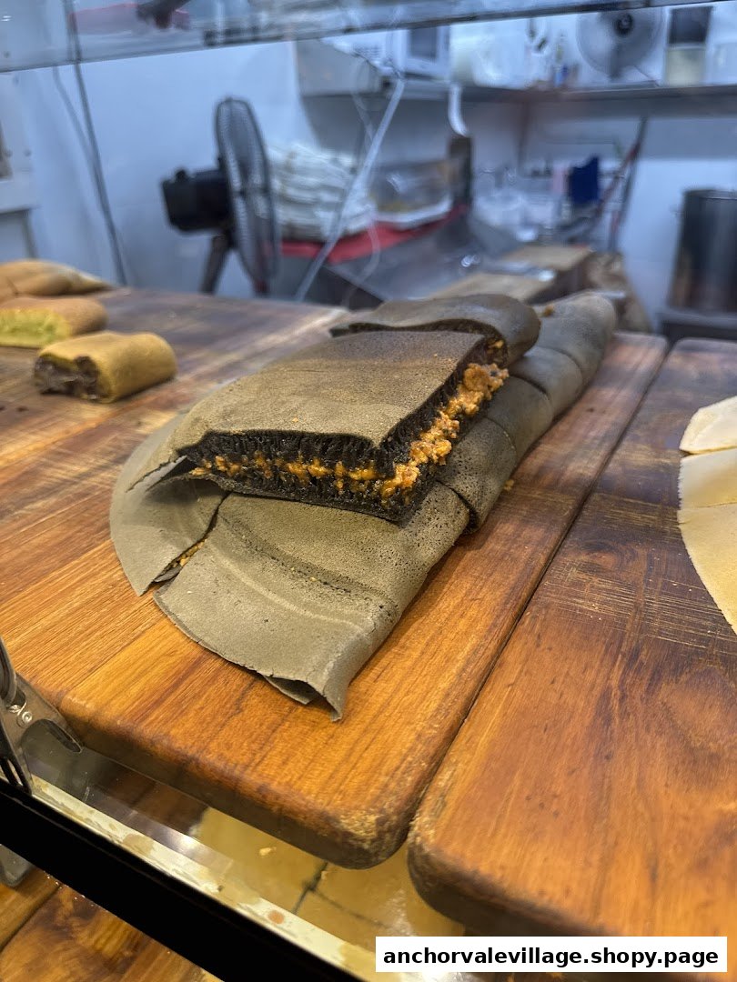 Close-up of freshly made Munchi Pancakes, including a dark charcoal pancake with peanut filling, displayed on wooden boards.