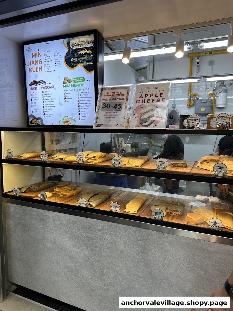 A display counter at Munchi Pancakes showcasing various pancakes and a digital menu board.