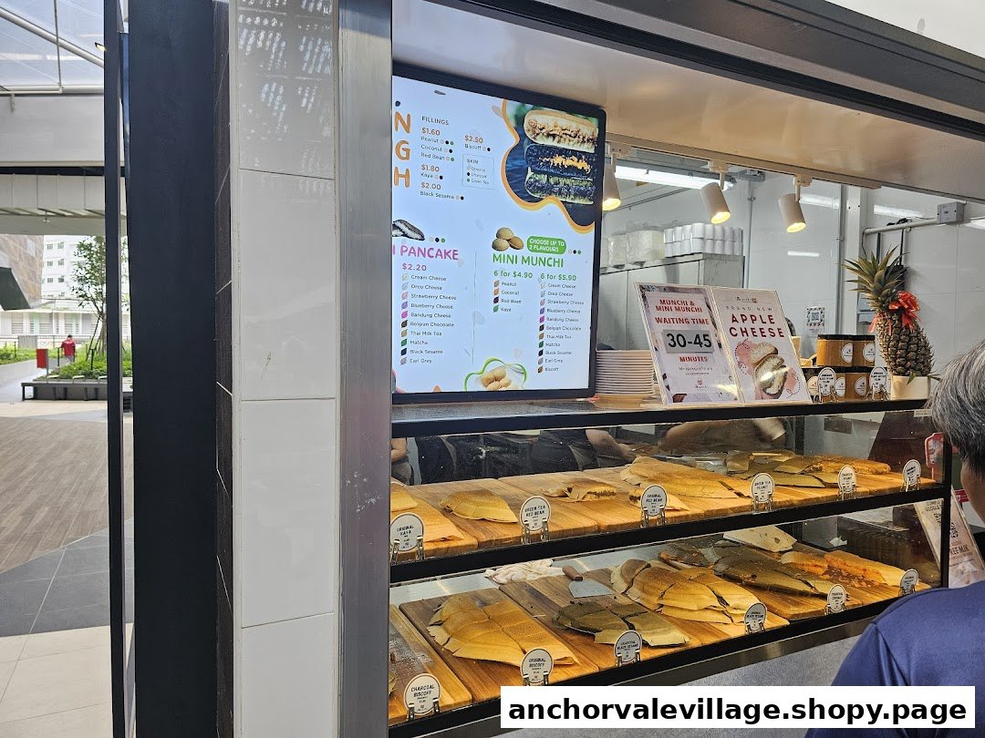 A Munchi Pancakes stall featuring a digital menu, a display of fresh pancakes, and a customer.