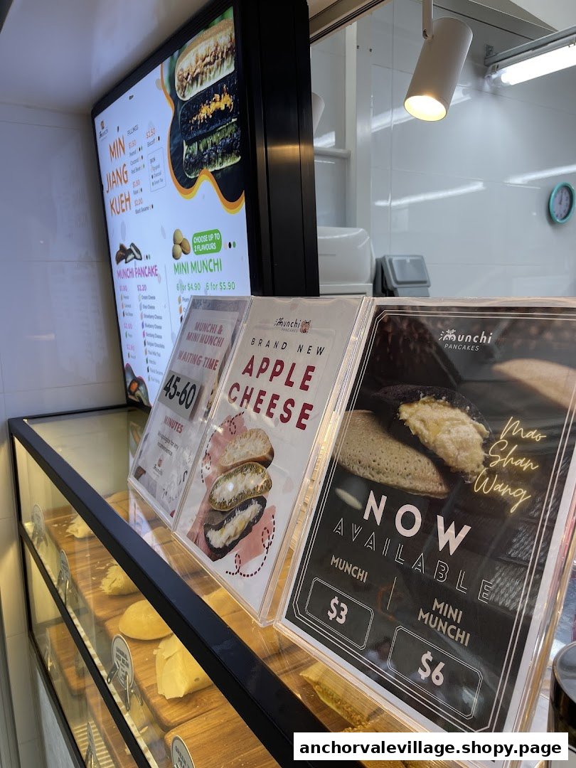 A counter view of Munchi Pancakes, featuring digital menu boards, promotional displays, and a display case.