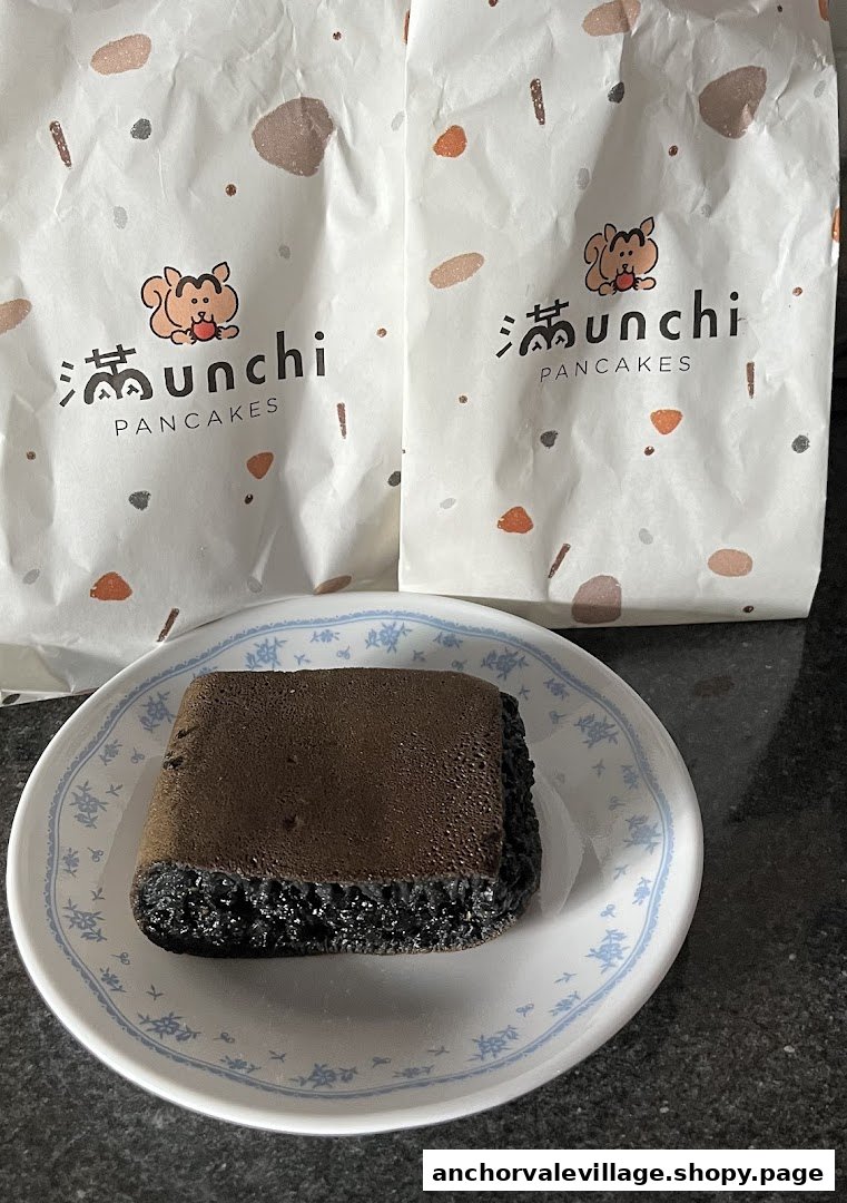 A dark chocolate pancake on a plate with two Munchi Pancakes branded bags in the background.