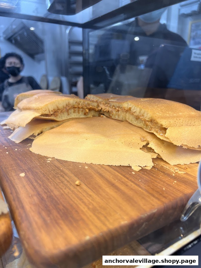 Freshly made Munchi Pancakes with peanut filling displayed on a wooden board, with staff in the background.