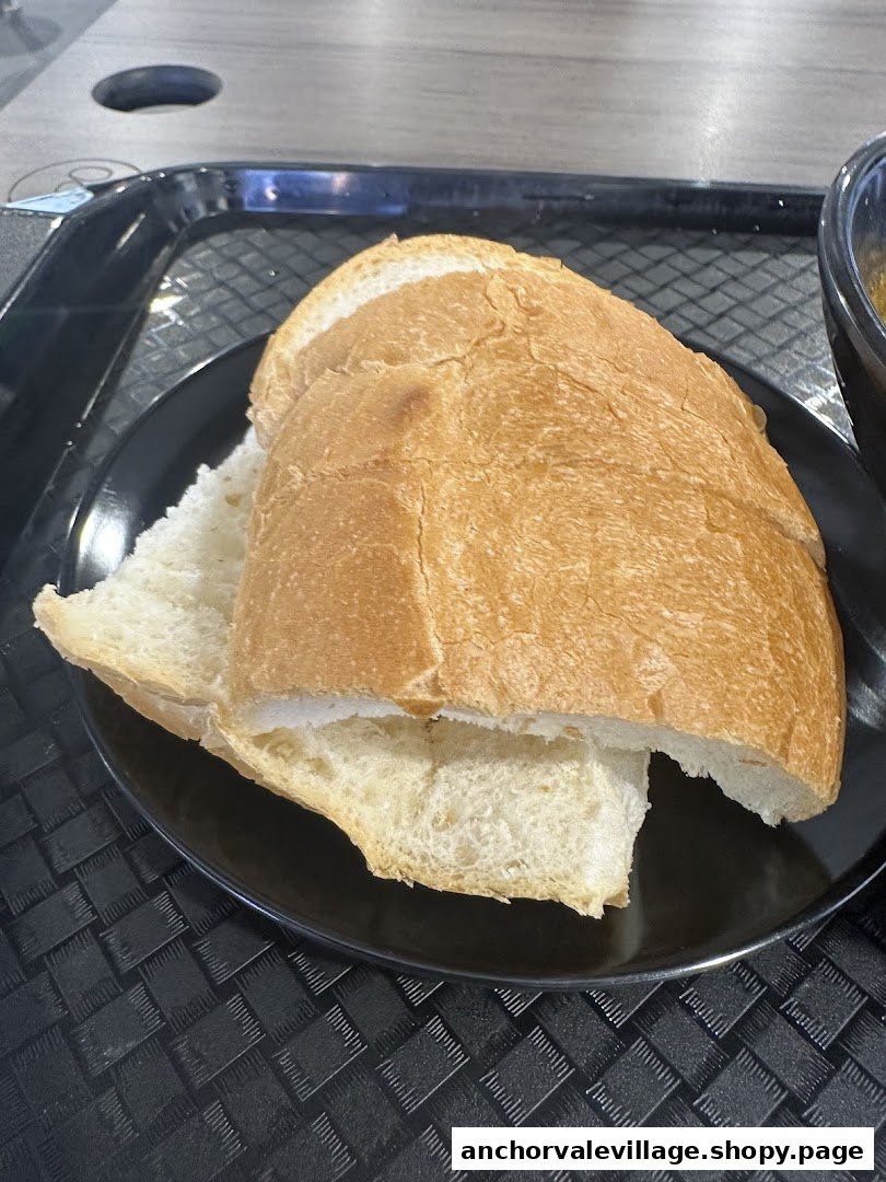 Freshly sliced bread on a black plate, ready to accompany a delicious curry meal.