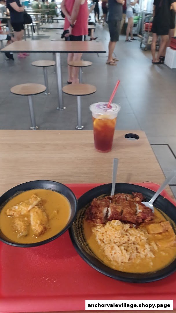 Two bowls of curry dishes, one with rice and fried chicken, and an iced tea on a table.
