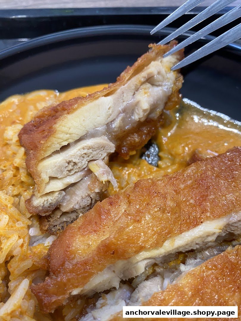 A close-up of crispy fried chicken served with rich curry sauce and rice.