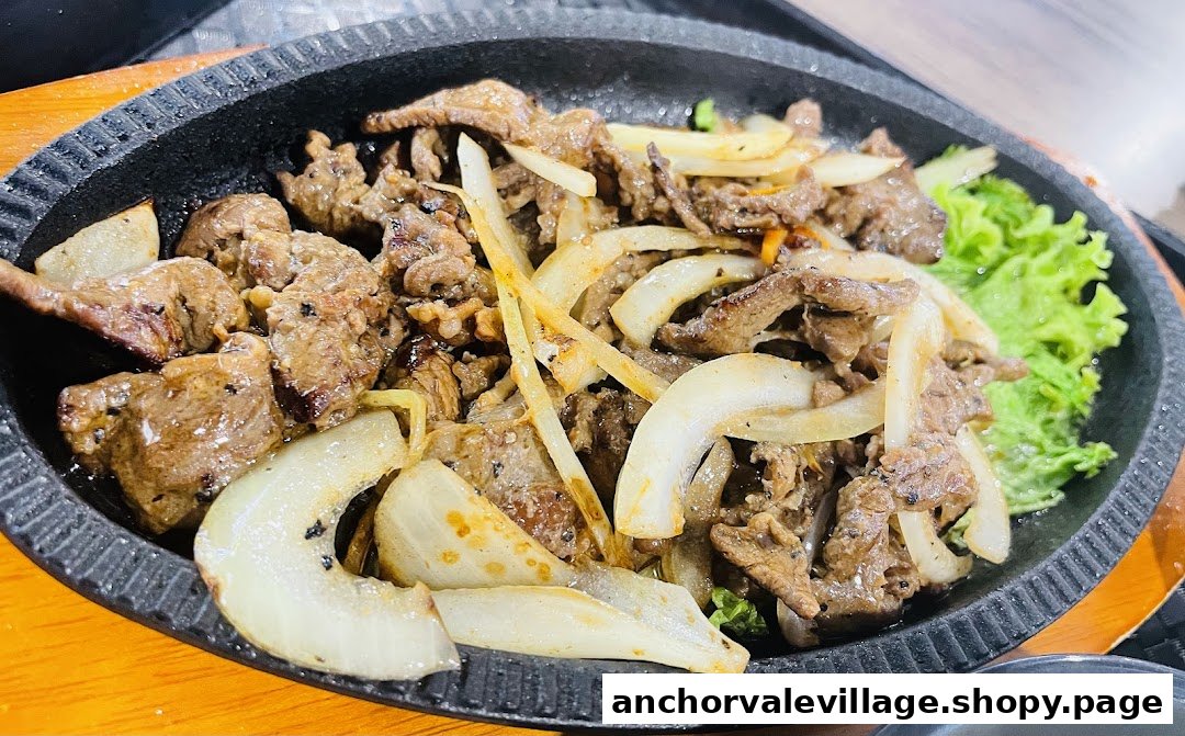 A sizzling plate of stir-fried beef with onions and fresh lettuce.