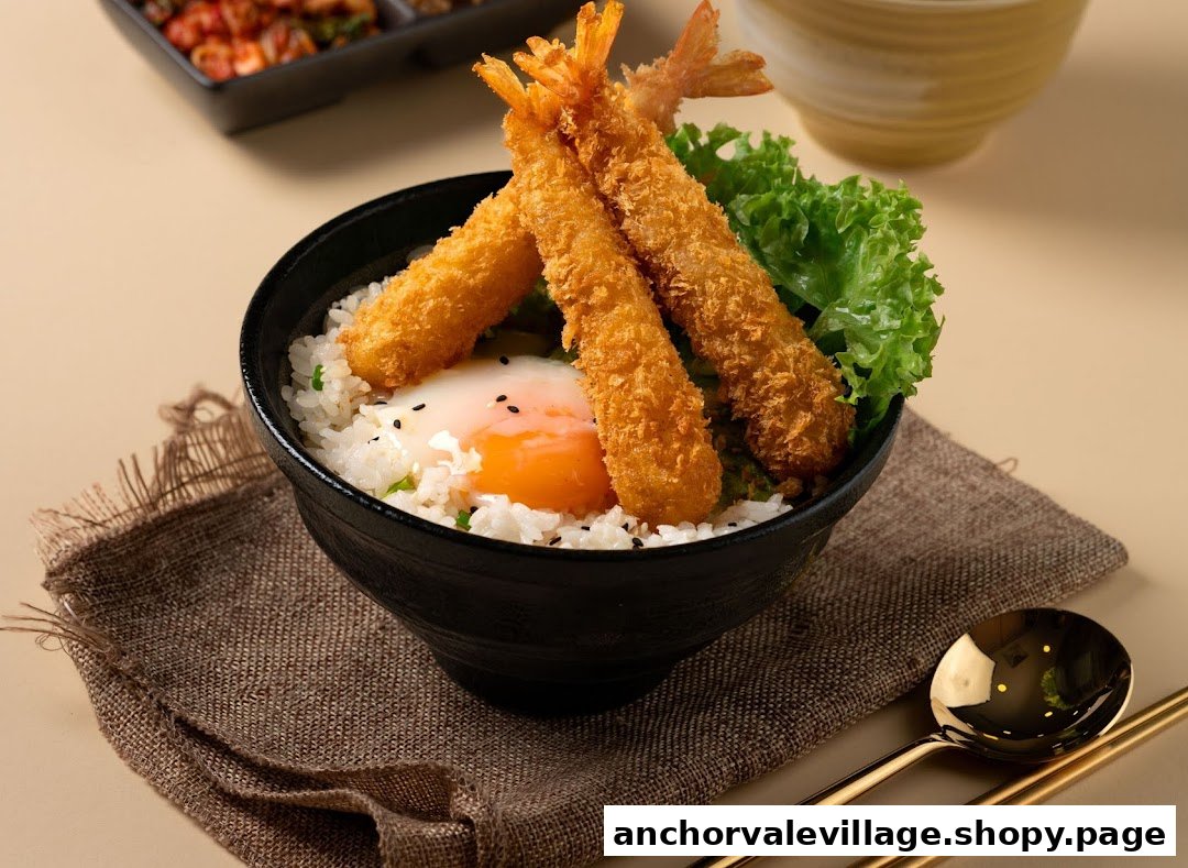 A delicious bowl of rice topped with crispy fried prawns, a soft-boiled egg, and fresh lettuce.