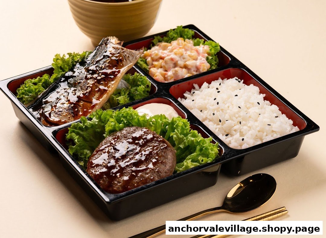 A beautifully presented Japanese bento box featuring grilled fish, hamburger steak, rice, and salad.