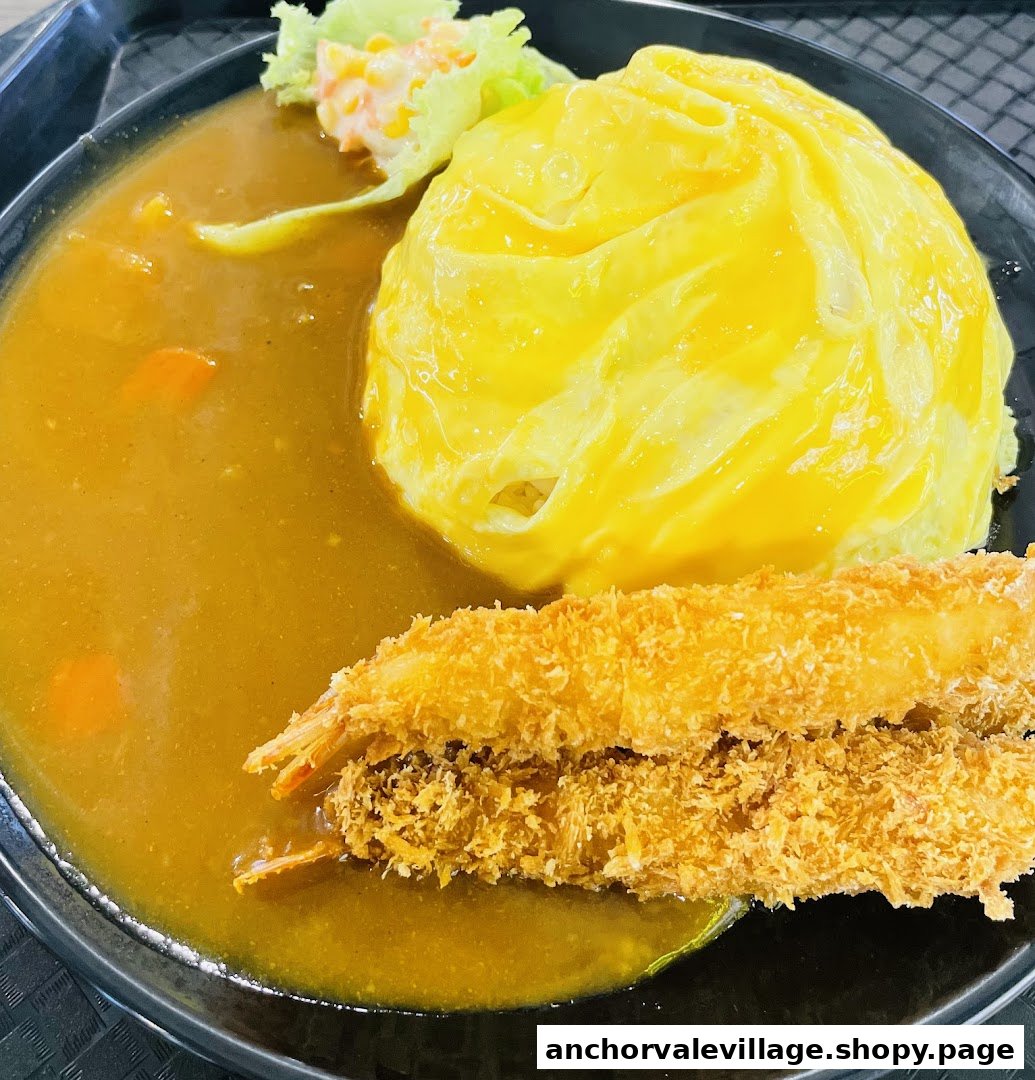 A delicious plate featuring Japanese curry, fluffy omurice, and crispy ebi fry with a side salad.