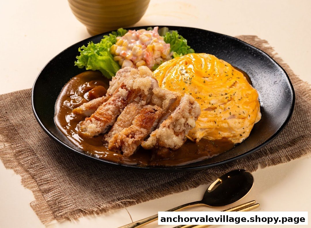 A delicious plate of Japanese curry with crispy fried chicken, fluffy omurice, and a side salad.