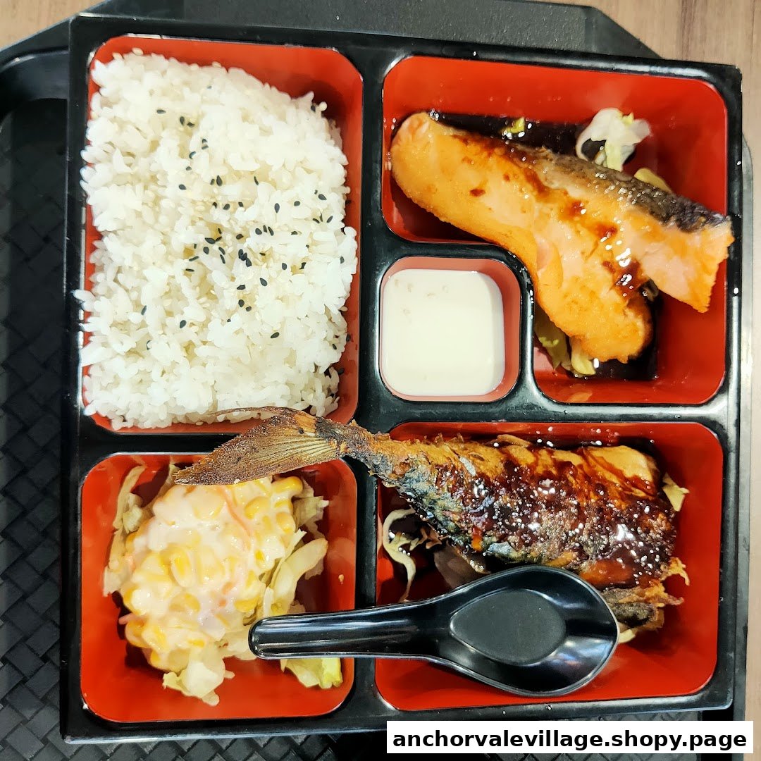 A Japanese bento box featuring rice, grilled salmon, grilled mackerel, and a side salad.
