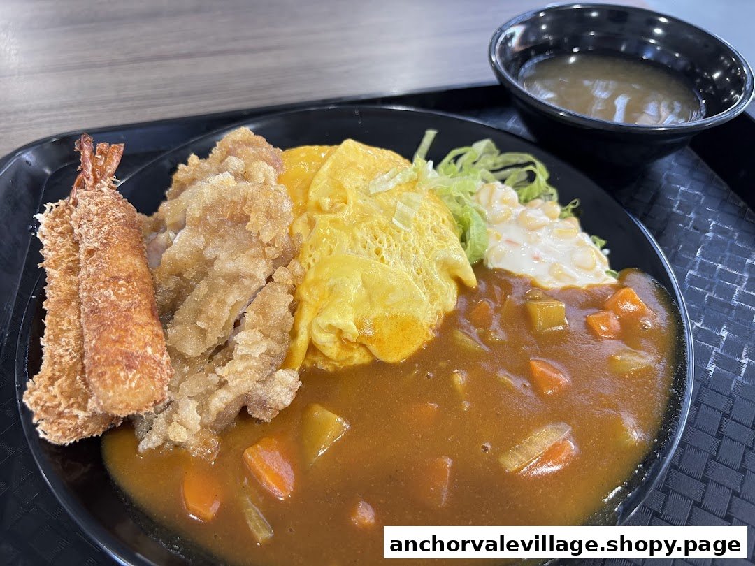 A delicious Japanese curry dish with fried chicken, tempura prawns, omelette, and a side of salad.