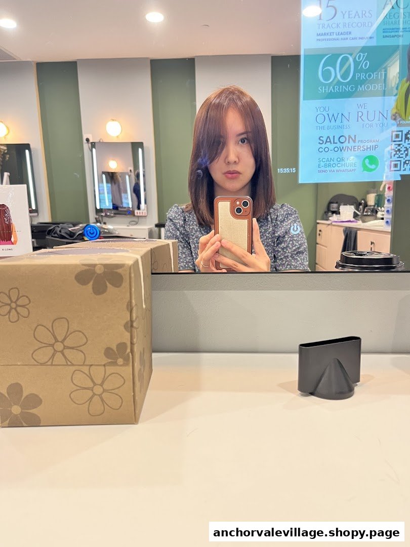 A person takes a mirror selfie in a modern hair salon, showcasing the interior and a digital display.