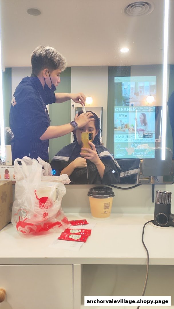 A stylist applies product to a client's hair in a modern salon setting, reflected in a mirror.