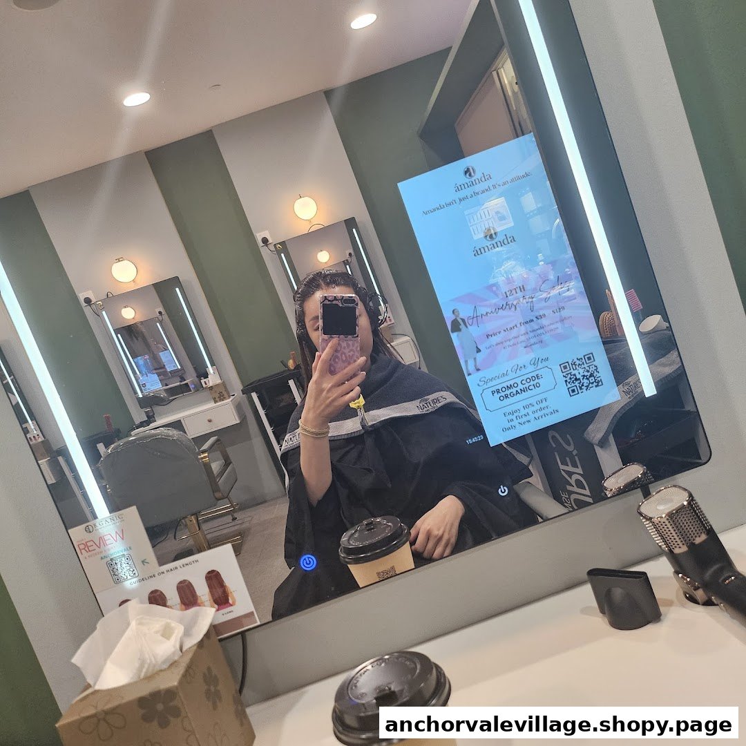 A customer sits in a modern salon chair, reflected in a smart mirror displaying promotions, at Organic Express Hair Color Lab.