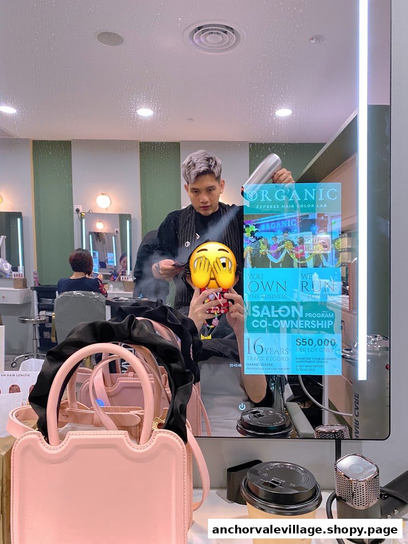 A hair stylist works on a client's hair in a modern salon, reflected in a smart mirror displaying promotional content.