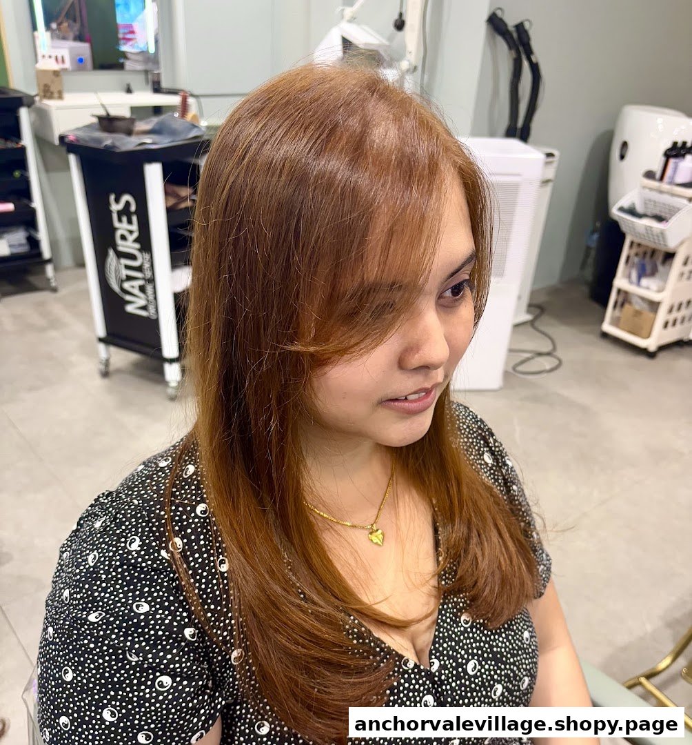 A woman showcasing her freshly colored, reddish-brown hair inside a salon, highlighting the results of a hair treatment.