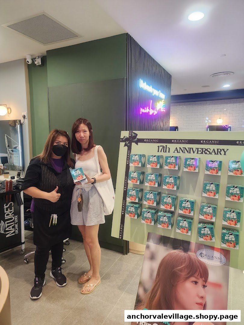 Two women, one staff and one customer, stand by an 'Organic Express Hair Color Lab' display, showcasing products.