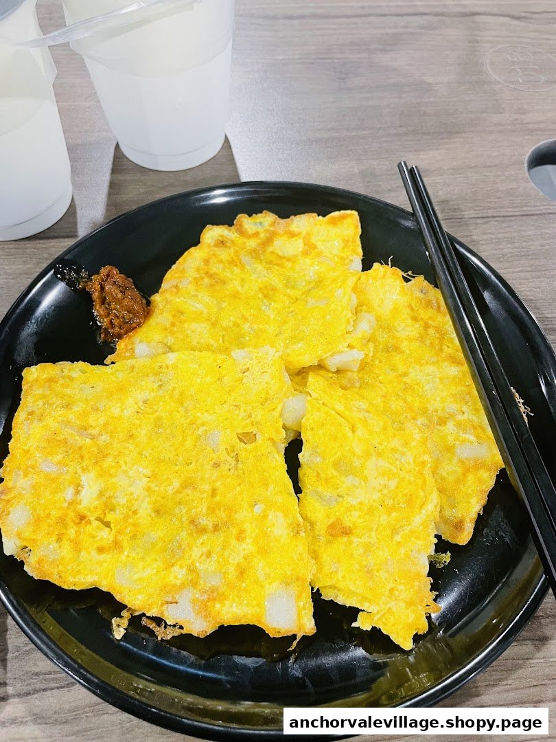 A plate of golden fried carrot cake with chili and chopsticks, ready to be enjoyed.