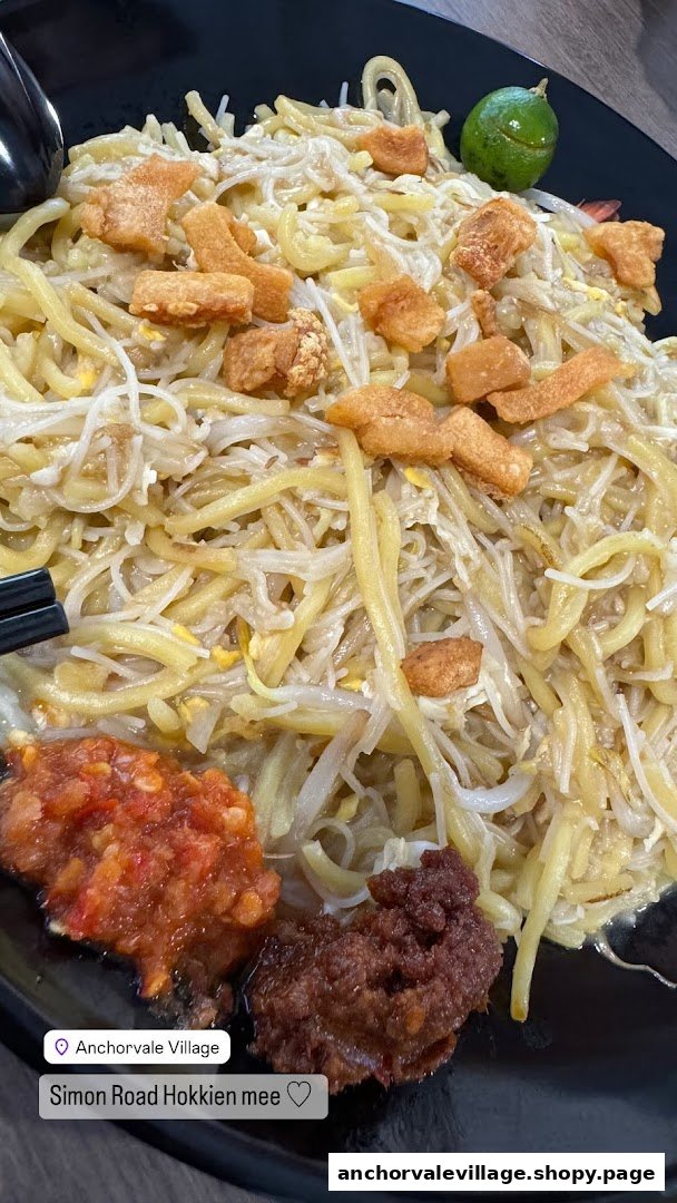 A close-up of a delicious plate of Hokkien Mee with crispy pork lard and chili.