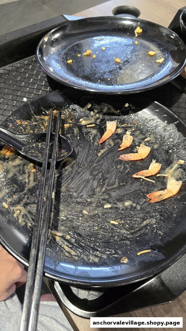 Empty plates with leftover shrimp tails and chopsticks, indicating a satisfying meal.
