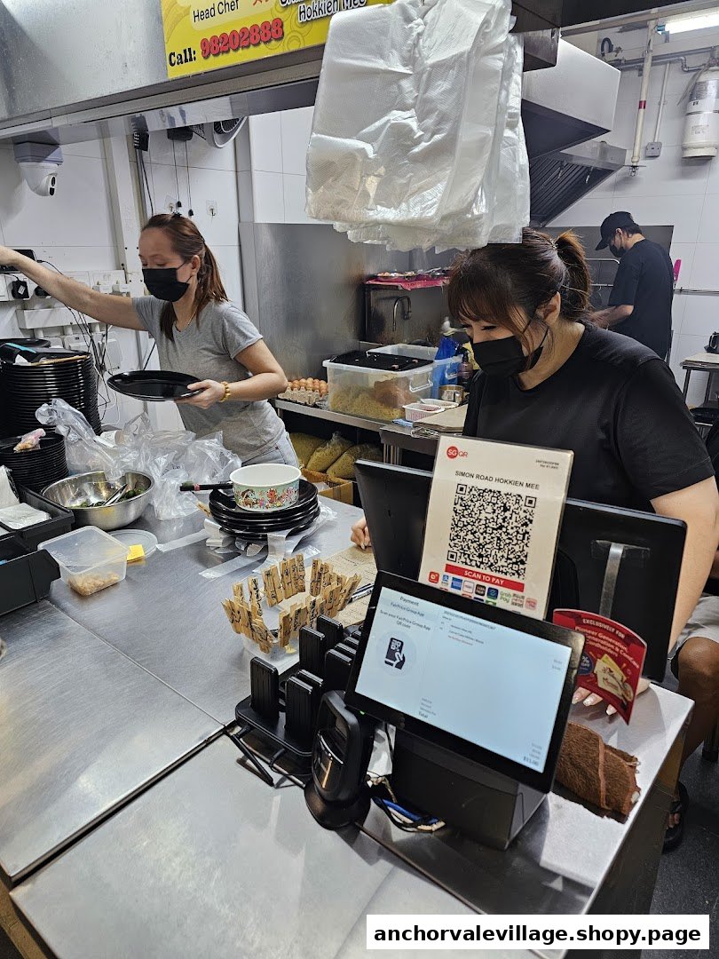 Staff prepare orders and manage payments at the bustling counter of Original Simon Road Hokkien Mee.