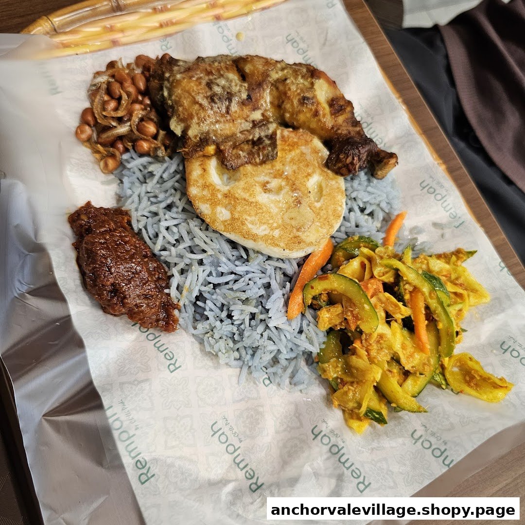 A vibrant plate of Nasi Kerabu with grilled chicken, fried egg, sambal, and pickled vegetables.