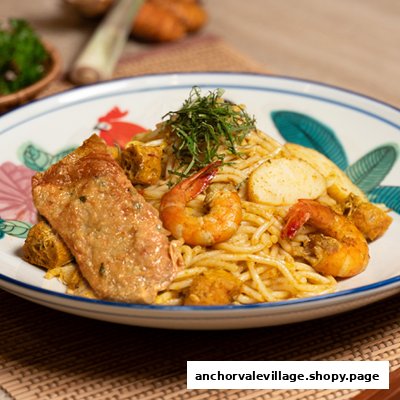 A vibrant plate of noodles with prawns, tofu, and a fried fritter, garnished with fresh herbs.