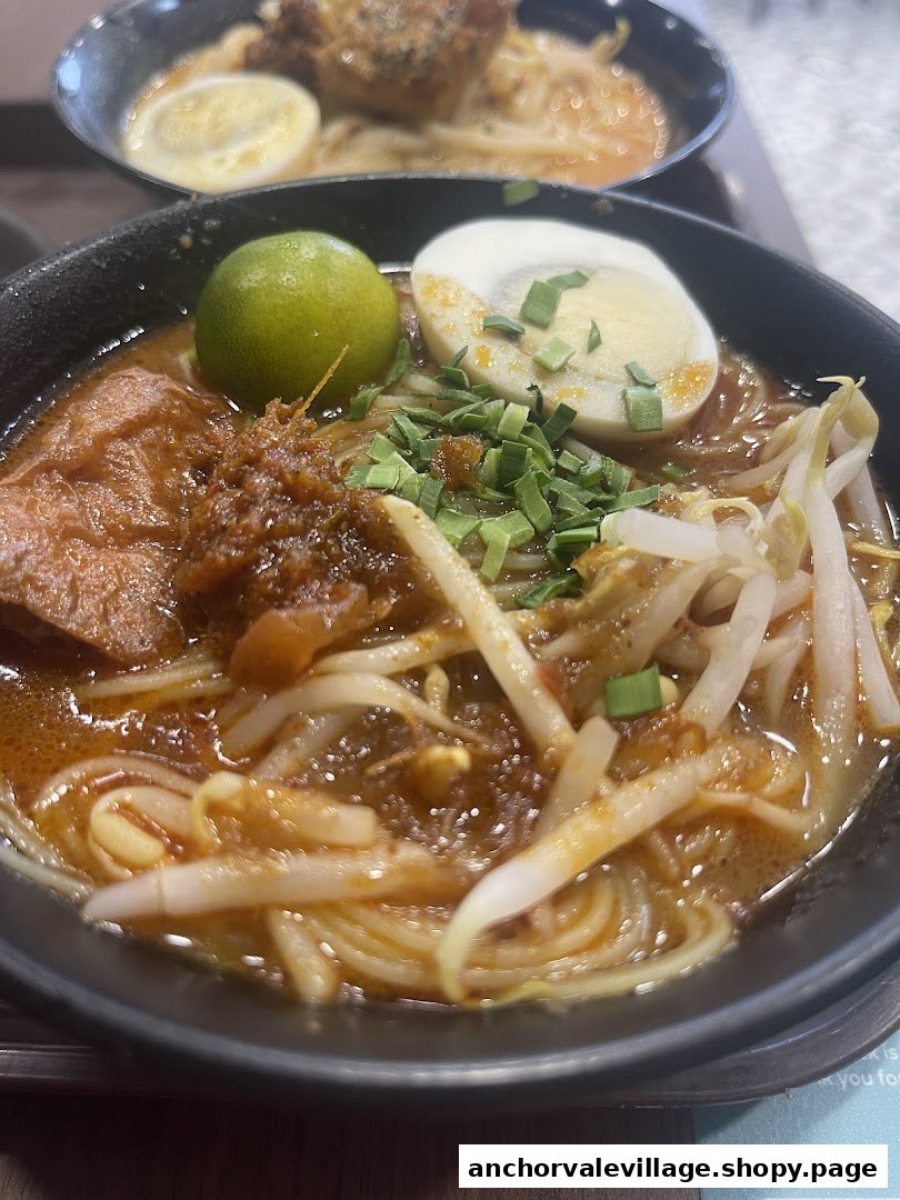 Two bowls of flavorful noodles, one in focus with lime, egg, and sprouts, ready to be enjoyed.