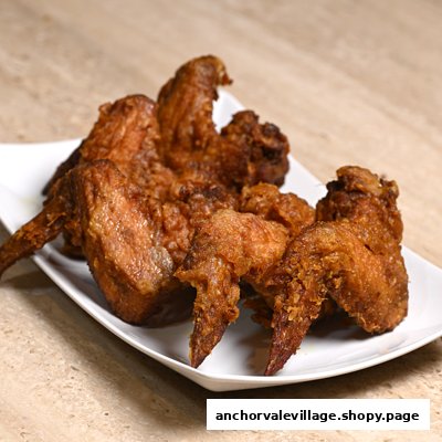 A white plate filled with several crispy, golden-brown fried chicken wings.