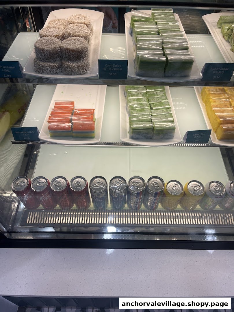 A display case showcasing various traditional kueh and canned beverages.