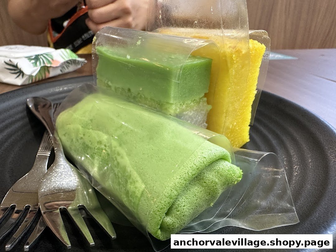 A plate of vibrant green and yellow traditional desserts, individually wrapped, with forks.