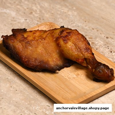 A perfectly roasted chicken leg quarter served on a rustic wooden tray.