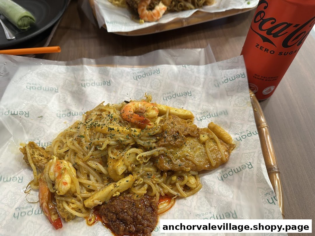 A close-up of delicious stir-fried noodles with prawns and a Coca-Cola Zero Sugar can on a table.