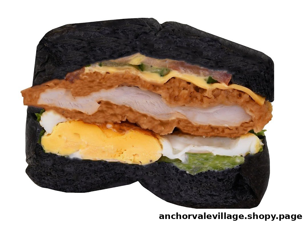 A cross-section of a gourmet sandwich featuring a black bun, fried chicken, egg, and cheese.