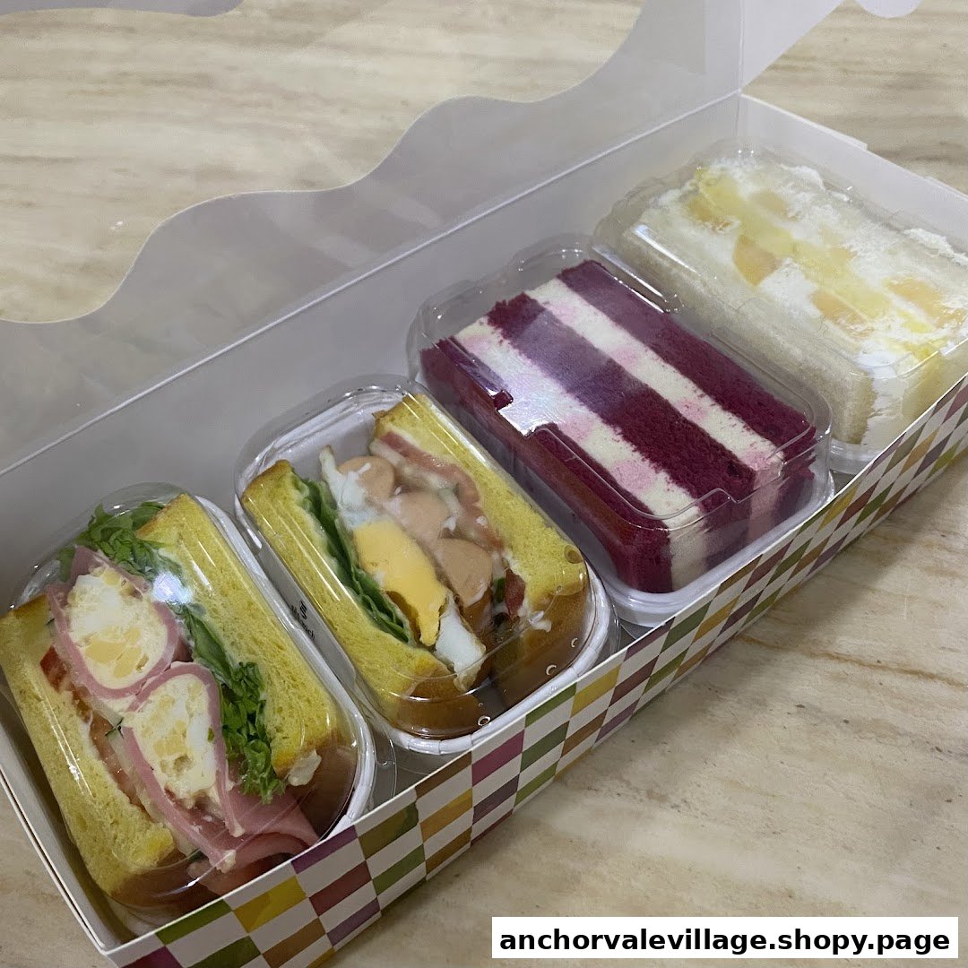 A takeaway box containing two sandwiches and two slices of cake, including red velvet.
