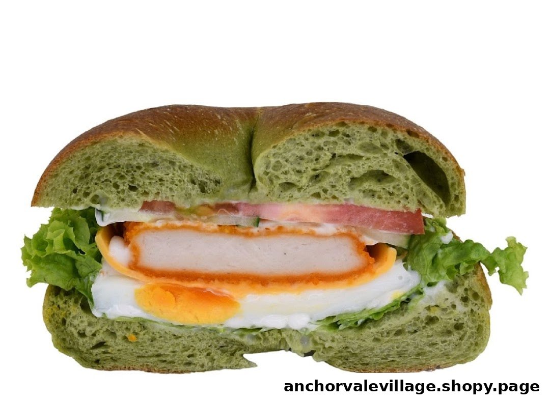 A vibrant green bagel sandwich filled with crispy chicken, egg, lettuce, and tomato.
