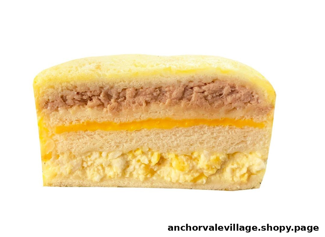 A cross-section of a multi-layered sandwich featuring tuna, cheese, and egg salad fillings.