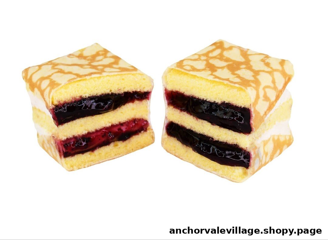 Two square slices of layered cake with sponge, cream, and berry fillings, topped with a patterned crepe.