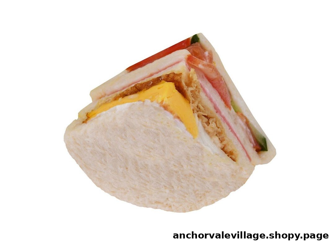 A close-up of a multi-layered sandwich featuring egg, tuna, ham, tomato, and cucumber.