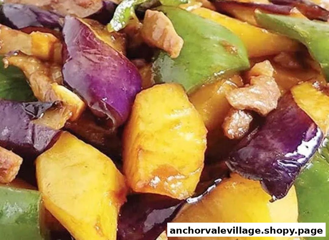 A vibrant close-up of stir-fried eggplant, potatoes, and bell peppers with meat pieces.