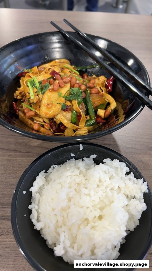 A vibrant bowl of spicy mala hotpot ingredients with peanuts and chili, served with a side of white rice.