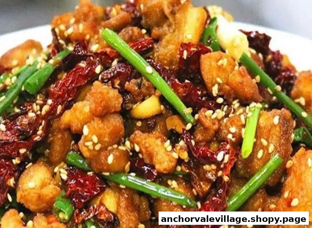 A close-up of spicy fried chicken with dried chilies, green onions, and sesame seeds.